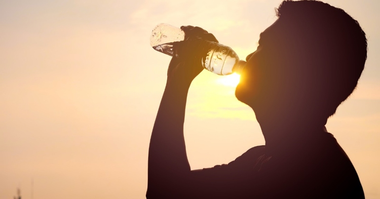 a man drinks from a water bottle on a hot, sunny day