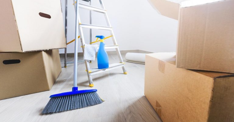a broom leans against a ladder and other cleaning supplies in a room with packed boxes