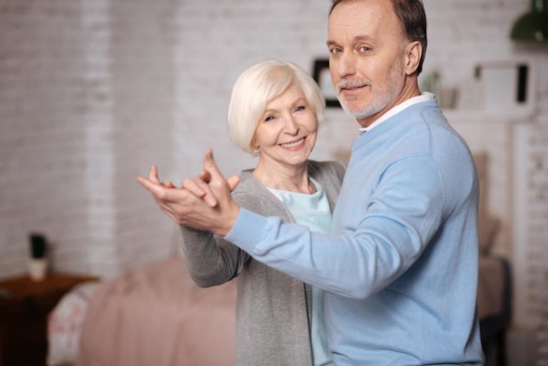 A senior man and woman dance in their new home.