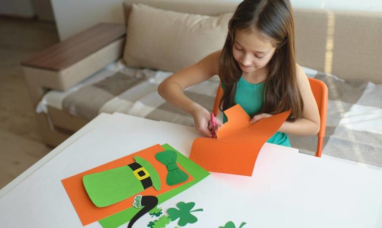 A young girl cuts out a Saint Patrick's Day craft.
