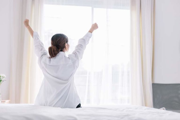 Lady sitting on the side of the bed preparing for the new day