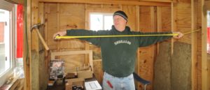 A man measuring the inside of his tiny home during construction. 