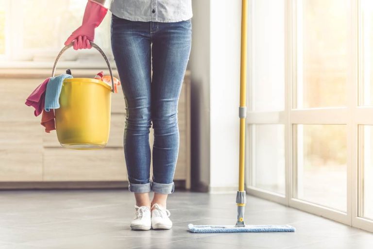 A close-up shot of a woman holding a mop and a bucket