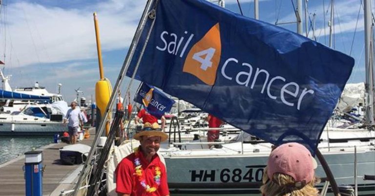 Man posing in front of Sail 4 Cancer flag