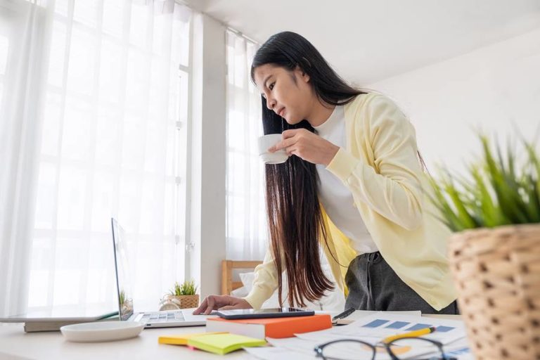 Lady working on laptop while enjoying her drink