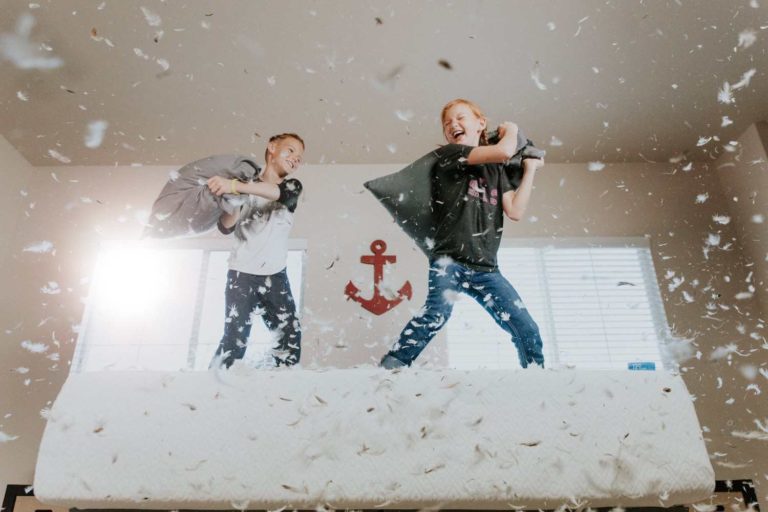 Two kids having fun with a pillow fight