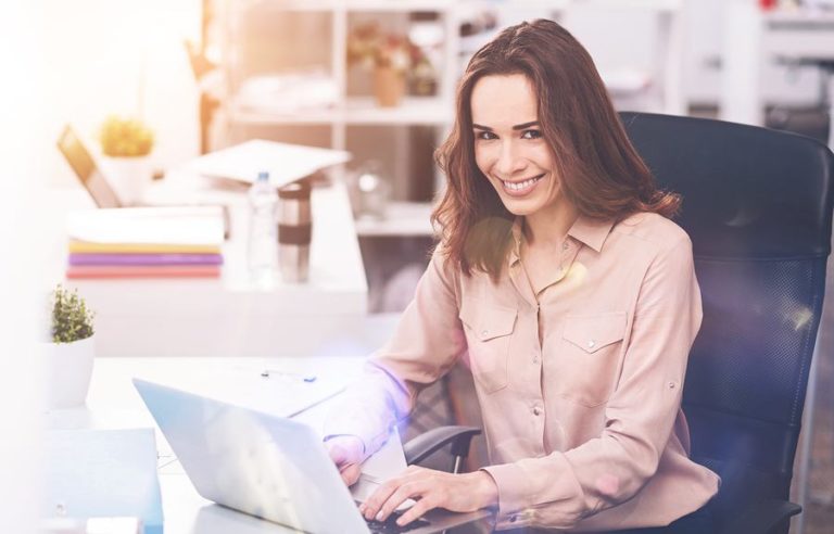 LAdy happily typing on laptop