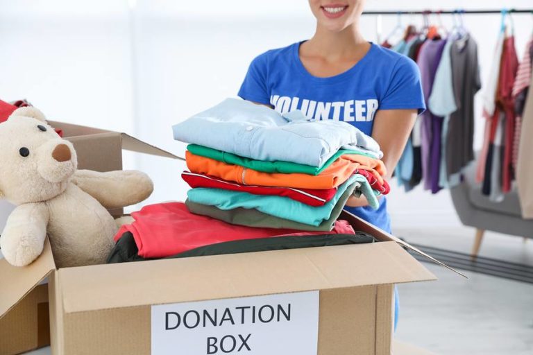 Lady neatly packing clothing items into donation box