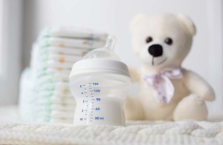 Childrens teddy bear placed next to baby bottle