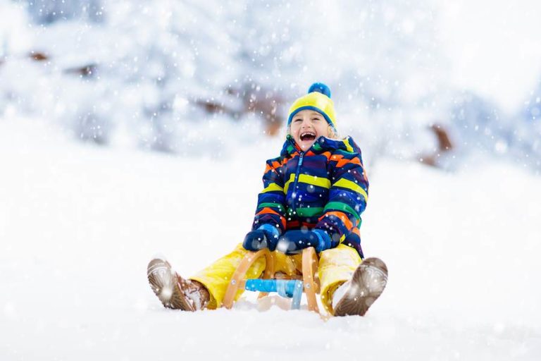 Child sledding through white powdery snow