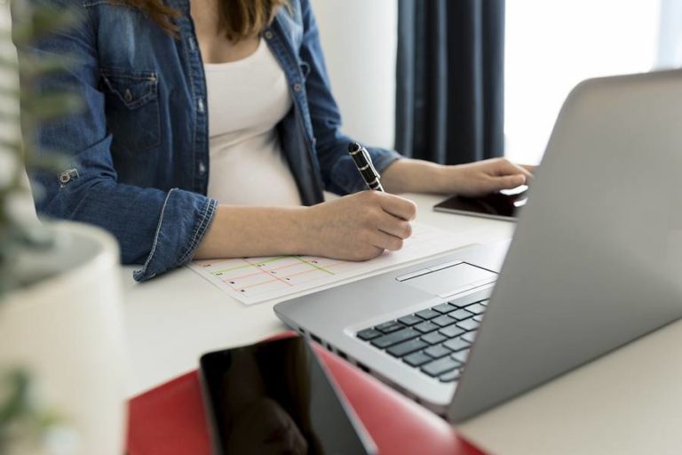 Lady working hard and writing with laptop nearby