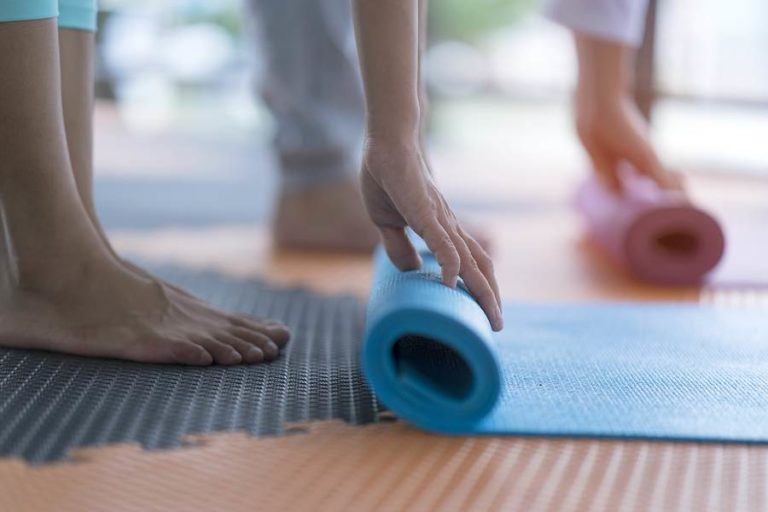 Pair of people rolling up yoga mats