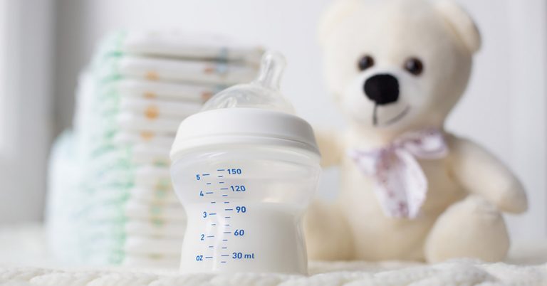 A teddy bear and baby bottle with diapers.