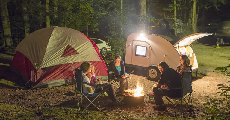 A family of five gathers around a campfire