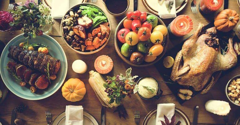 A dinner table is covered with a Thanksgiving feast