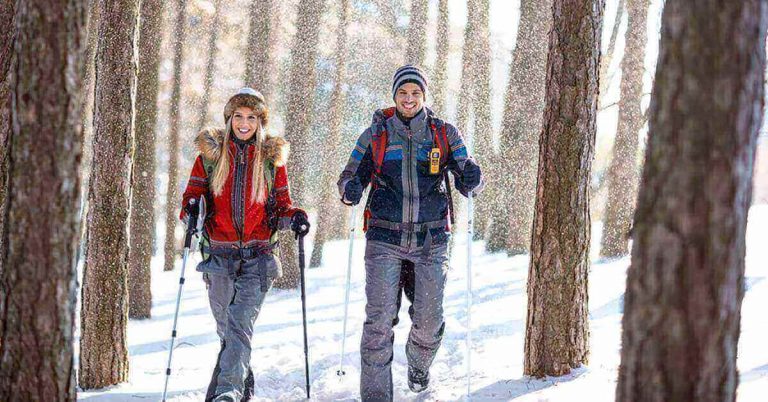 A young couple snowshoe in the forest.