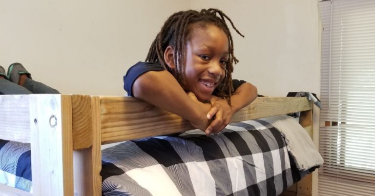 young child smiling in a bunk bed provided by sleep in heavenly peace