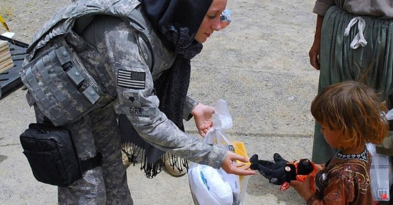 Soldier gives toy to a child.