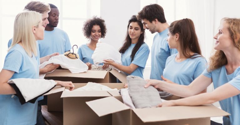 group of teenagers sorting through boxes of clothes for donation