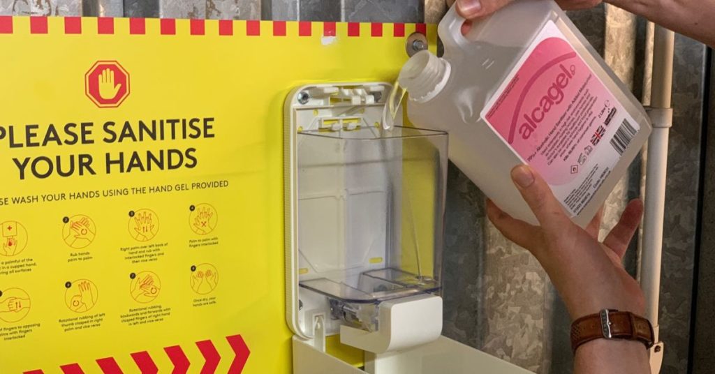 a StorageMart employee refills a hand sanitizer station