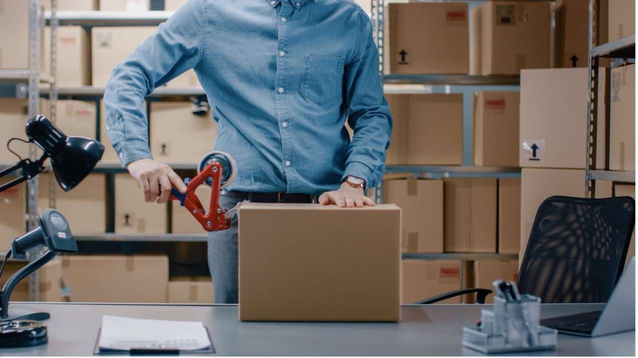 Guy taping boxes up in warehouse