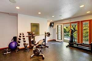 A small gym with free weights, an elliptical, and bench.