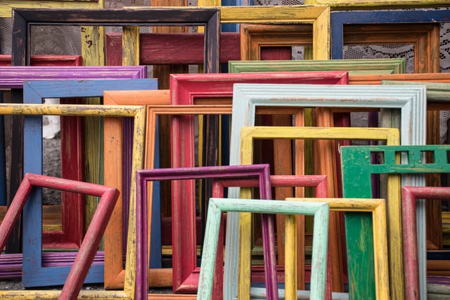 An assortment of colorful wooden picture frames waiting to be packed and stored.
