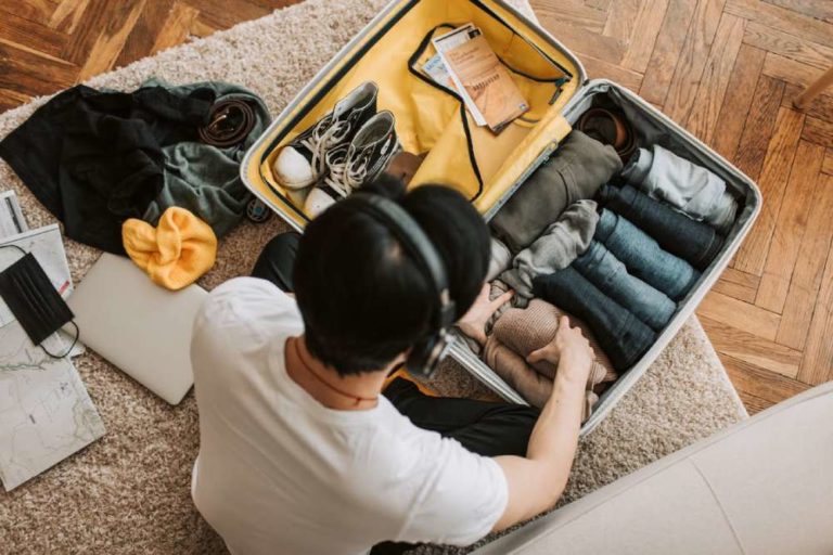 Man listening to music as he sits on the floor packing his bags