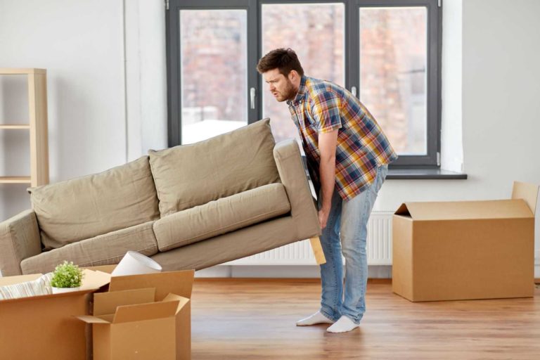Man moving couch in his living room