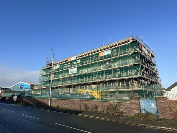 Tall, large building that has lots of scaffolding and many windows as it appears to be under construction