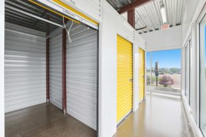 Spacious indoor climate-controlled self storage units with bright yellow roll-up doors and clean indoor hallway at a StorageMart facility.
